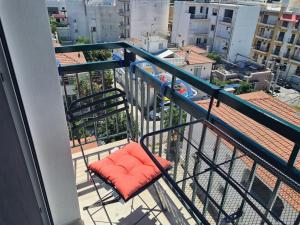 una silla con una almohada naranja en el balcón en Fay's luxury loft, en Volos