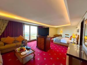 a hotel room with a couch and a bed and a television at Le Royal Amman in Amman