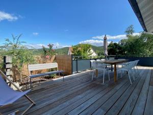 a deck with a table and chairs and an umbrella at Aux Magnolias, Maison proche Colmar et Munster in Zimmerbach