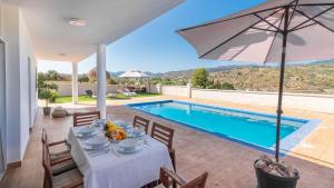 a villa with a swimming pool and a table and an umbrella at Casa Rio Grande 2 Tolox by Ruralidays in Tolox