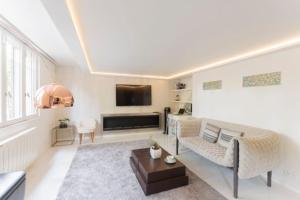 ein Wohnzimmer mit einem Sofa und einem TV in der Unterkunft Luxury modern two bedroom duplex by Roland Garros in Paris