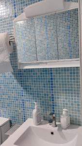 uma casa de banho com um lavatório e uma parede de azulejos azuis em Metro La Salut em Badalona