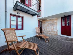 2 sillas en una terraza de madera con puerta roja en Prédio da Estação, en Oporto