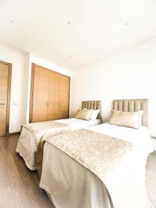 Habitación con 2 camas, paredes blancas y suelo de madera. en Pristigia rabat, en Rabat