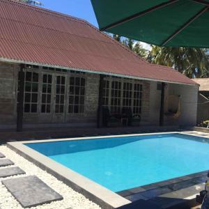 einem Pool vor einem Gebäude mit rotem Dach in der Unterkunft Villa Almond Mayo in Gili Trawangan