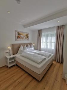 a bedroom with a large white bed and a window at Feine Bleibe in Eben im Pongau
