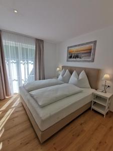 a white bedroom with a large bed and a window at Feine Bleibe in Eben im Pongau