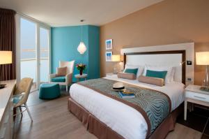 ein Hotelzimmer mit einem großen Bett und einem Stuhl in der Unterkunft Herods Dead Sea – A Premium Collection by Fattal Hotels in Ein Bokek
