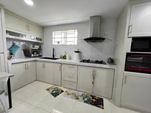 cocina con armarios blancos y suelo de baldosa en ORKED HOMESTAY, en Alor Setar