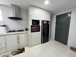 a kitchen with white cabinets and a black refrigerator at ORKED HOMESTAY in Alor Setar