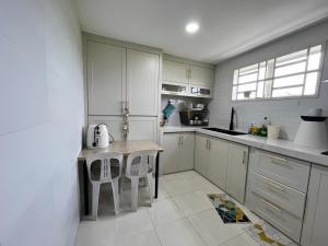 a white kitchen with a table and chairs in it at ORKED HOMESTAY in Alor Setar