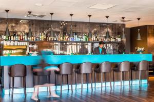 a bar with leather chairs and a bartender at Motel One Edinburgh-Princes in Edinburgh