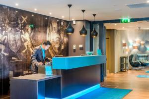 a man standing at a counter in a lobby at Motel One Edinburgh-Princes in Edinburgh