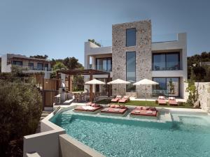 a house with a swimming pool with chairs and umbrellas at Ismet Villa, a SeaView Glorious Hideaway, By ThinkVilla in Akrotiri