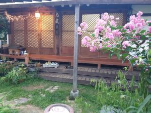 a wooden house with pink flowers in the yard at Gugangjae Hanok Stay in Jeonju