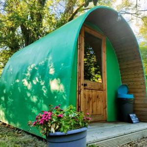 a green dome house with a door and flowers at Battle Pods and Bells in Battle