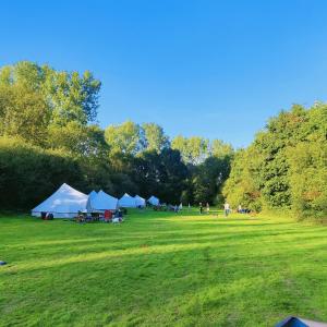 a group of tents in a grass field at Battle Pods and Bells in Battle