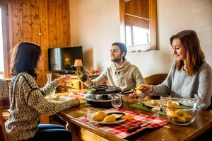a group of three people sitting at a table with food at Résidence Goélia Les Chalets de Saint-Sorlin in Saint-Sorlin-dʼArves