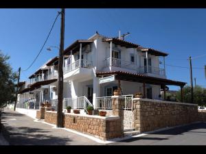 uma grande casa branca com uma parede de pedra em Papoulias Rooms em Elafonisos