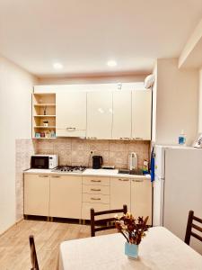 Label Apartment في تبليسي: مطبخ بدولاب بيضاء وطاولة وثلاجة