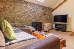 sala de estar con pared de piedra y TV en Gîte Bed & Bedot, en Fauvillers