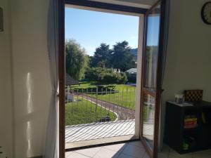 an open sliding glass door with a view of a yard at Casa del vecchio faggio - Nebbiuno Lago Maggiore in Nebbiuno