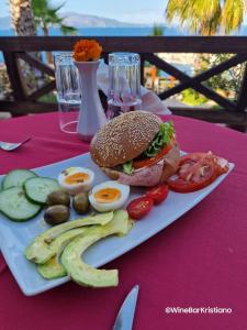 a plate with a sandwich and eggs and vegetables on a table at Villa Kristiano 21 in Sarandë