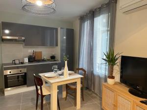 a kitchen with a table with chairs and a television at Sur la route des vignerons - Clim - 1 Chambre in Courthézon