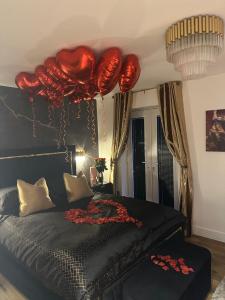 Casa Amor - Kinky Hotel UK في ساوثهامبتون: غرفة نوم مع بالونات حمراء معلقة على سرير