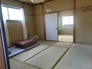 una habitación vacía con una cama y una puerta en 하루카오후나에 민숙 en Tsushima