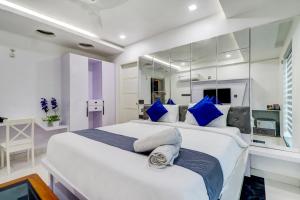 a bedroom with a large white bed with blue pillows at Hotel Brundavan International Guntur in Guntūr
