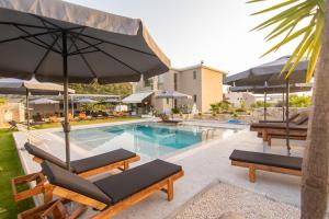 a pool with chairs and umbrellas next to a swimming pool at Charisma Luxury Suite & Rooms in Pérdika
