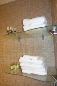 a bunch of towels on a glass shelf in a bathroom at Miss Nefeli - Marvelous Stone Apartment in Perdika-Aegina in Aegina Town