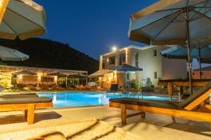 a pool at a hotel with tables and umbrellas at Charisma Luxury Suite & Rooms in Pérdika