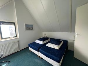 a bedroom with a bed with blue sheets and a window at Hello Zeeland - Vakantiehuis Stern 207 in Breskens