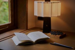an open book on a table with a lamp and a pen at tamao-たま靑- in Kyoto