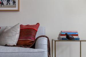 a couch with a pillow and a side table with books at Primary Located Splendid 2BR flat near Hyde Park in London