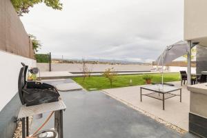 eine Terrasse mit Tisch und Sonnenschirm in der Unterkunft Villa Oasis en Madrid con 3Hab, 4baños y elegante piscina in Villanueva del Pardillo