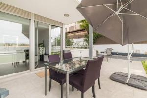 einen Glastisch mit Stühlen und einem Sonnenschirm in der Unterkunft Villa Oasis en Madrid con 3Hab, 4baños y elegante piscina in Villanueva del Pardillo