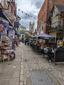 a cobblestone street with people sitting in chairs in an outdoor market at STABLE HOUSE - Eton WINDSOR in Windsor