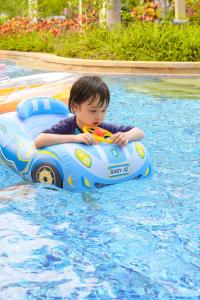 un jeune garçon roule dans une piscine gonflable dans l'établissement Sheraton Sanya Haitang Bay Resort, à Sanya