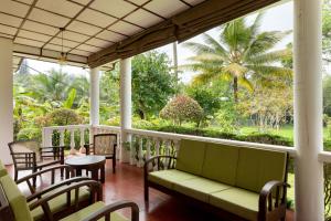 une terrasse couverte avec un canapé, des chaises et un palmier dans l'établissement Surveyor's Residence Bungalow, à Kandy