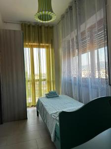 ein Schlafzimmer mit einem Bett und einem großen Fenster in der Unterkunft Kennedy Apartment in Quattromiglio