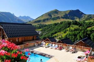 a resort with a swimming pool and mountains in the background at Résidence Goélia Les Chalets des Ecourts in Saint-Jean-dʼArves