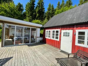 un cobertizo rojo con un banco en una terraza de madera en Stuga Ljungsjön en Falkenberg