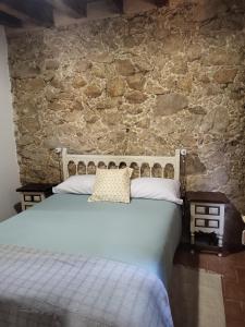 una camera con letto e parete in pietra di La Casa El Cura a Madrigal de la Vera