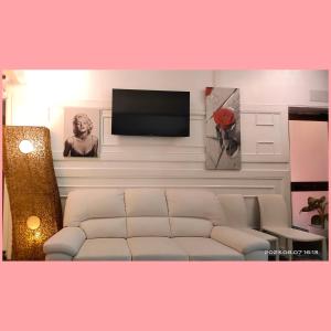 ローマにあるRosa Italia Hotel Romaの白いソファと薄型テレビのあるリビングルーム