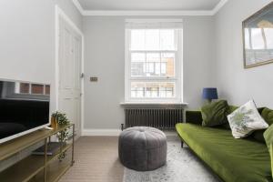 a living room with a green couch and a television at Lovely 2-bedroom apartment in Shoreditch in London
