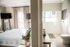 a bedroom with a bed and a bathroom with a toilet at The Whale on Main B&B in Hermanus