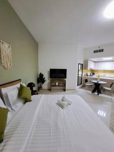 a large white bed with two towels on it in a room at Gorgeous Sea side Studio with Stylish Interior-RAK in Ras al Khaimah